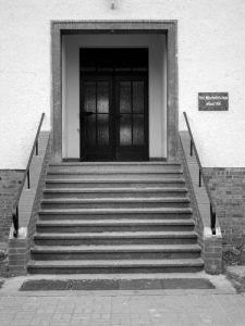 Einer der ersten Nachkriegsbauten in Paulinenaue war das Laborgebäude des Instituts. Heute heißt es Mitscherlichhaus. Am schlicht gehaltenen Eingangsbereich befindet sich eine Namenstafel